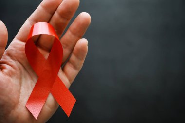 İnsan bağışıklık yetmezliği virüsü hastalığının sembolü. Kırmızı kurdele. Yardım eli ve destek. Arkaplan.