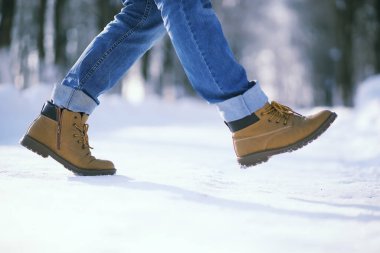Karla kaplı patika boyunca adımlar. Bir adam kışın parkta yürür.