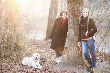 Sonbahar bahçesinde annesiyle köpek gezintisine çıkmış genç bir kız.