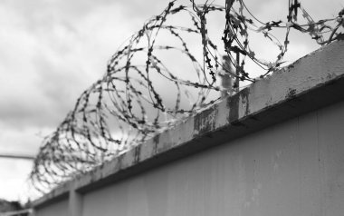 Çitin üzerinde dikenli tel olan beton duvar.
