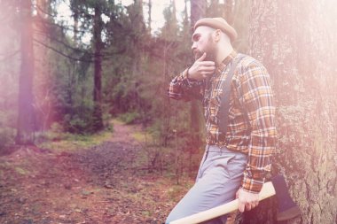 Büyük bir balta ile sakallı bir oduncu ağaç felling önce inceler