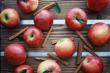 Tahtadaki taze elmalar. Kırmızı elma hasadı. Masada meyve ve tarçın var..