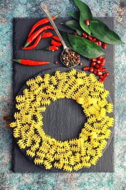 Taş zeminüzerine pişmemiş makarna. Baharatlar ve baharatlar, baharatlı biber ve baharatlarla.