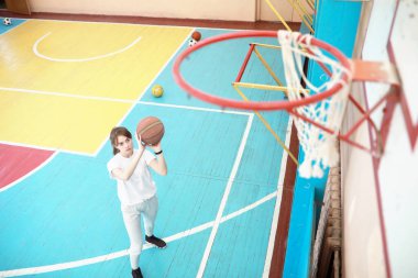 Spor salonunda basketbol oynayan genç bir kız.