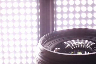 Ekipman kameramanı ve fotoğrafçı. Masadaki lensler parlak lambaların arka planına karşı. Kamera camının yansımasında parla ve bokeh.