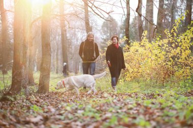 Sonbahar bahçesinde annesiyle köpek gezintisine çıkmış genç bir kız.