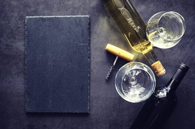 Masada bir bardak kırmızı şarap. Siyah şişe ve bir bardak şarap..