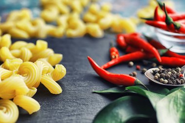 Taş zeminüzerine pişmemiş makarna. Baharatlar ve baharatlar, baharatlı biber ve baharatlarla.