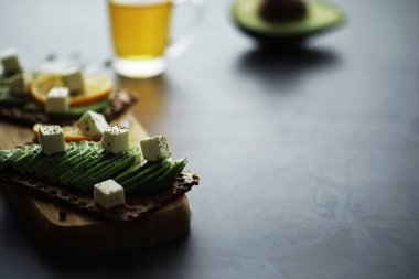 Avokado yemek tarifleri. Tahta kesme tahtasında servis edilen olgun yeşil avokado..