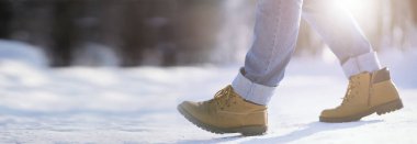 Karla kaplı patika boyunca adımlar. Bir adam kışın parkta yürür.