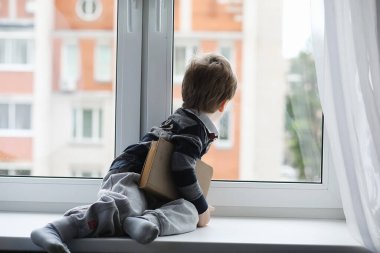 Küçük çocuk bir kitap okuyor. Çocuğun pencerenin önünde oturur ve dersler için hazırlar. Bir çocuk pencere üzerinde elinde bir kitapla