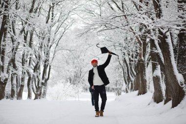 Parkta yürüyen bir adam. Kışın kar altında şemsiyeli genç bir adam..