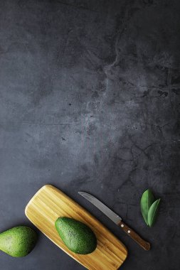 Avokado yemek tarifleri. Tahta kesme tahtasında servis edilen olgun yeşil avokado..