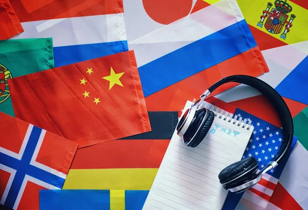 Learning foreign languages. Audio language courses. Background from countries flags and headphones on table.