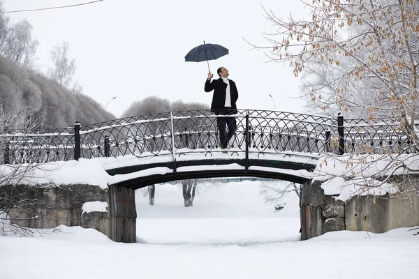 Winter walk with an umbrella.Man in coat with an umbrella, walk against the backdrop of the winter landscape, winter view