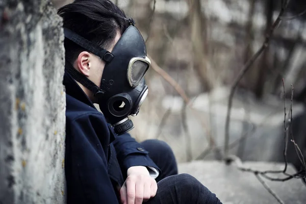The guy in the coat and gas mask. Post-apocalyptic portrait Asian masked from radiation. The boy is Korean in a mask from poisoning with gases. Post-nuclear mask on the Asian