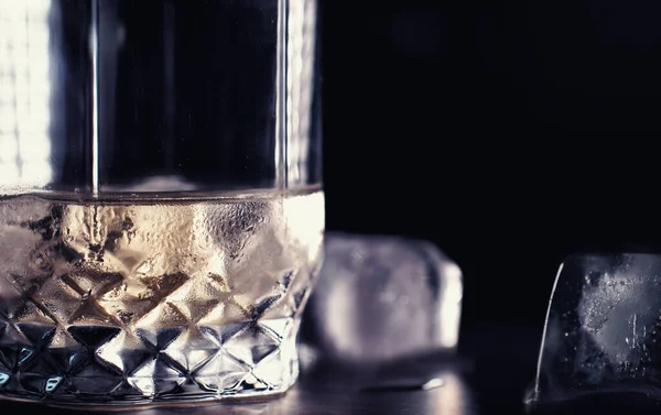 A glass of hard alcohol with ice on a bar counter. Whiskey with soda in glass. Advertising alcoholic drink.