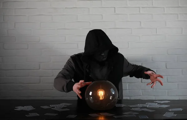A man with a fortune teller ball at the table