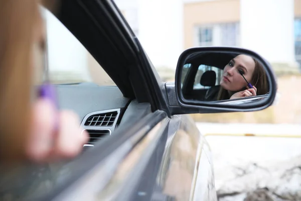 Girl doing makeup looking in the rear view mirror — Stock Photo, Image