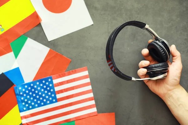 Learning foreign languages. Audio language courses. Background from countries flags and headphones on table.