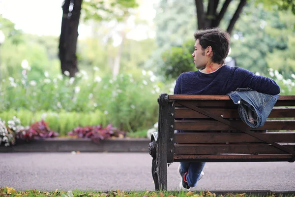 A young man walks in the park at lunch time. A man is on a walk in the city. A student in park