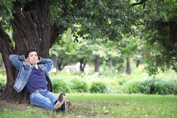 A young man walks in the park at lunch time. A man is on a walk in the city. A student in park