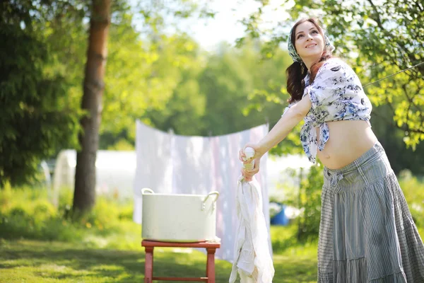 Pregnant woman hanging wash clothes on the rope for drying