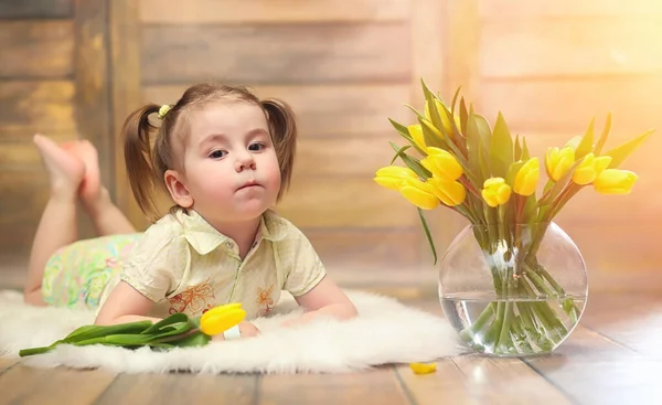一个带着一束黄色郁金香的小孩子 花瓶里有鲜花的男孩 女孩的礼物在女性假日与黄色郁金香在地板上 — 图库照片