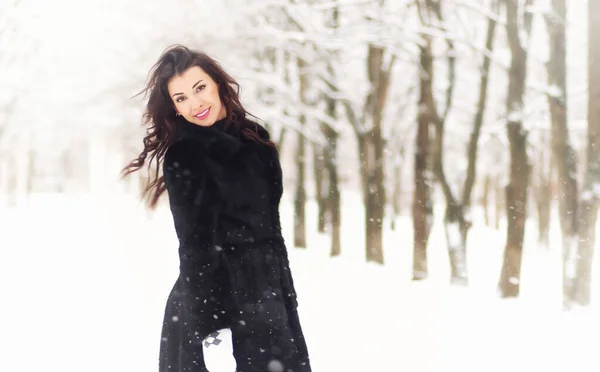 美丽的女人穿着保暖的衣服在雪地的冬季公园里散步 — 图库照片
