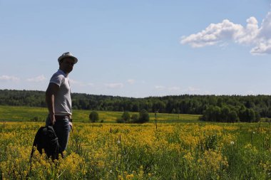 Genç adam bir yaz gününde sırt çantasıyla gezer.
