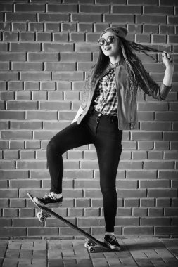 Genç hippi kız bir kaykay sürme. Kızlar kız şehirde bir kaykay ile yürüyüşe. Bahar spor bir kaykay ile sokakta