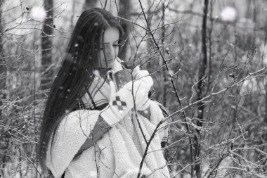 Kışın bulutlu bir günde, karla kaplı tarlalarda ve ormanlarda bir kız.