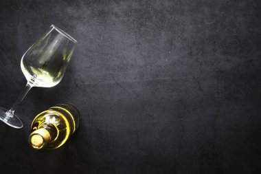 Masada bir bardak kırmızı şarap. Siyah şişe ve bir bardak şarap..