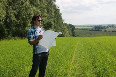 Genç bir adam doğadaki haritaya bakar, böylece kaybolmaz.