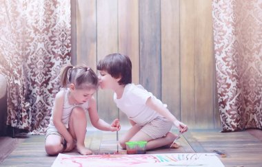 Küçük çocuklar tuvalette büyük bir kağıt parçasına resim yaparlar.