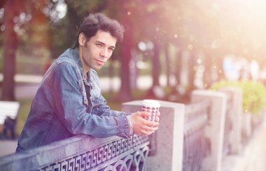 Genç bir adam öğle yemeği zamanında parkta yürür. Bir adam şehirde gezintiye çıktı. Park eden bir öğrenci.