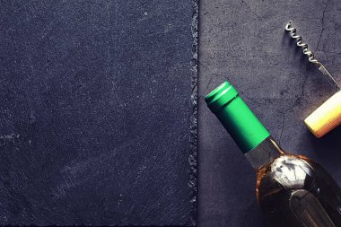 Masada bir bardak kırmızı şarap. Siyah şişe ve bir bardak şarap..