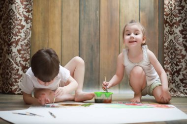 Küçük çocuklar tuvalette büyük bir kağıt parçasına resim yaparlar.