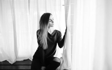 Genç bir kız büyük bir dairede dinleniyor.