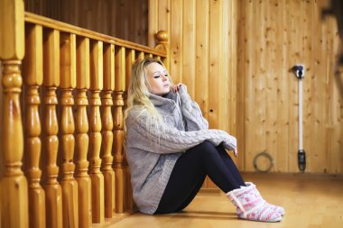 Genç bir kız kazakla merdivende oturuyor.