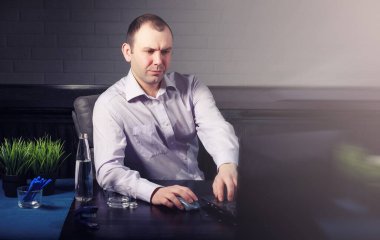 Masada oturan ve dizüstü bilgisayarda çalışan adam