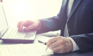 Müdür ofisteki bir dizüstü bilgisayarda çalışıyor. İşadamı çevrimiçi işlem yapıyor. Değiş tokuş internet üzerinden yapılıyor..