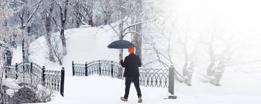 Şemsiyeli bir kış yürüyüşü. Şemsiyeli bir adam, kış manzarasının arka planında yürür, kış manzarası