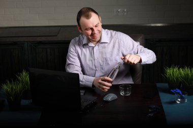 adam masasında oturan ve bir dizüstü bilgisayar üzerinde çalışan