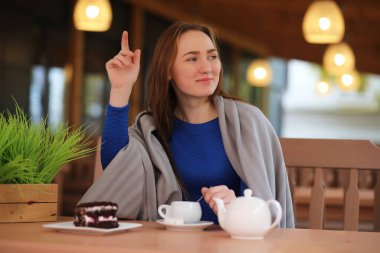 Kafede oturan ve tatlıyla çay içen genç bir kız.