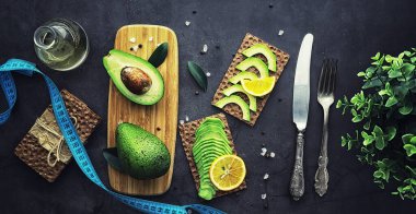 Avokado yemek tarifleri. Tahta kesme tahtasında servis edilen olgun yeşil avokado..