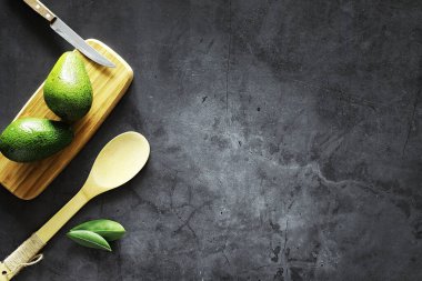 Avokado yemek tarifleri. Tahta kesme tahtasında servis edilen olgun yeşil avokado..
