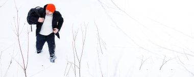 Kışın ormanda bir adam. Sırt çantalı bir turist kışın ormana gider..