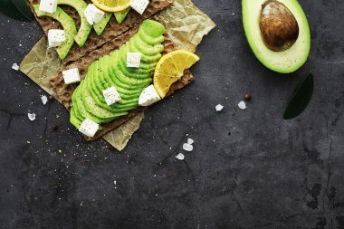 Avokado yemek tarifleri. Tahta kesme tahtasında servis edilen olgun yeşil avokado..