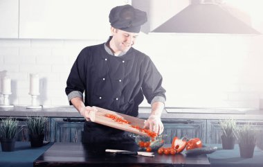 Adam mutfak masasında sebze pişiriyor.